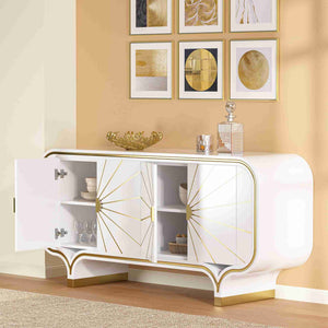 White and gold 4-door buffet with decorative items against a beige wall with framed art.